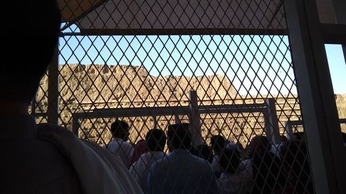 Rear view of people seen through fence