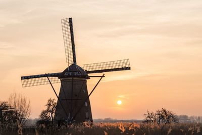 Traditional windmill against sky during sunset