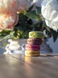 Close-up of macrons on wooden with flowers in white vase background table