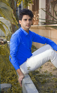 Portrait of young man standing against trees