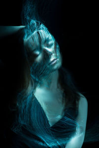 Digital composite image of young woman with light painting against black background