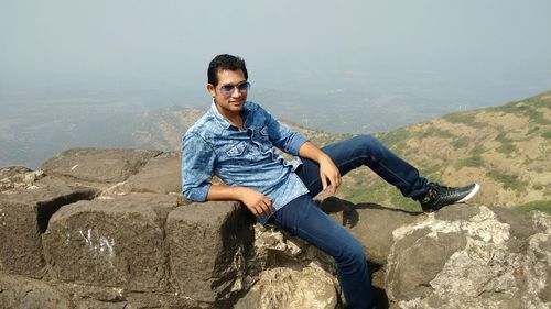 Handsome man resting on rocks on mountain