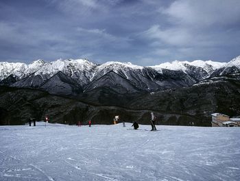 People skiing on snowcapped mountain against sky