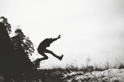 Silhouette of person jumping against clear sky