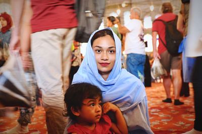 Portrait of mother wearing headscarf with daughter at temple