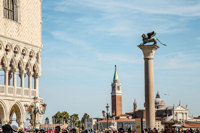 Statue in city against sky