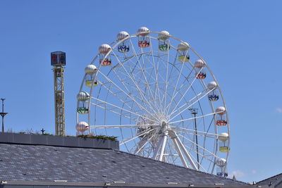 Low angle view of ferris wheel against clear blue sky