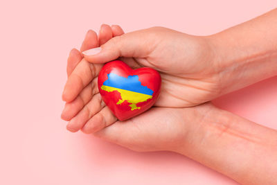 Cropped hand of person holding heart shape against white background