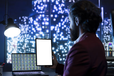 Rear view of man using laptop at office