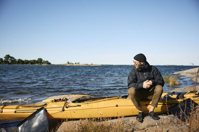 Man sitting on kayak on coast and looking away