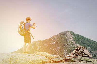 Man standing on rock against sky