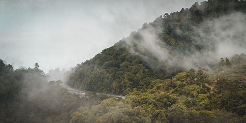 Clouds storm in between mountains and road.