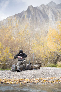 A fly fisherman prepares his gear in a beautiful mountain setting.