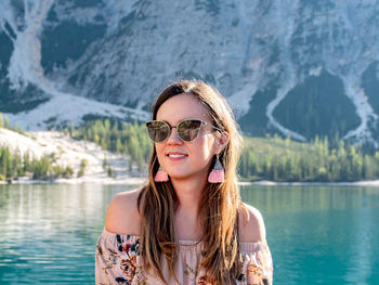 Portrait of an attractive young woman at a lake. woman wearing sunglasses and earrings.