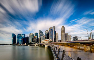 City at waterfront against cloudy sky