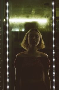 Portrait of woman standing against illuminated light
