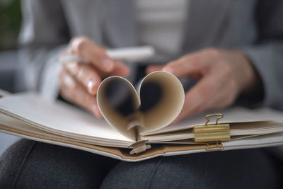 Midsection of businessman holding heart shape on table