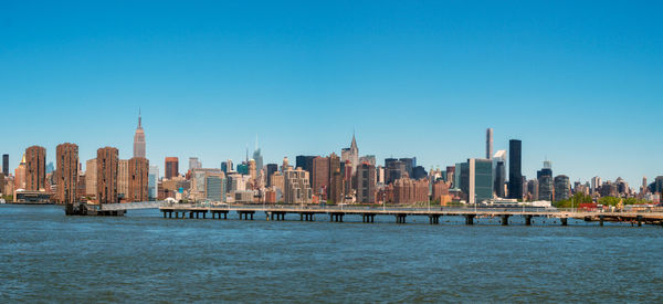 City at waterfront against blue sky