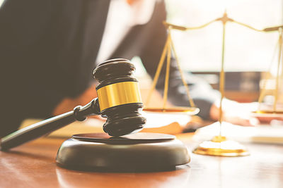 Midsection of judge working at desk with gavel and weight scale