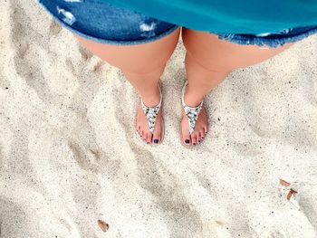 Low section of woman standing on sand at beach