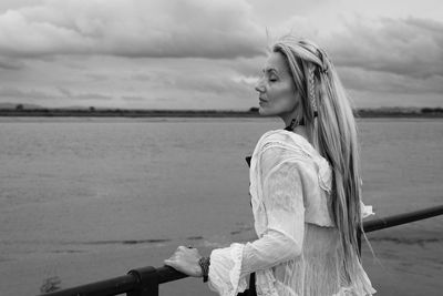 Woman standing by sea against sky