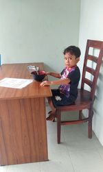 Young woman using mobile phone while sitting on chair at home