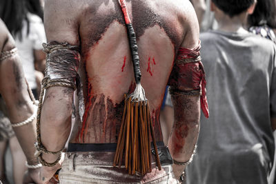 Rear view of shirtless man with wounds standing outdoors