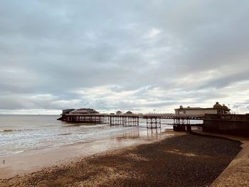 Pier on beach against sky