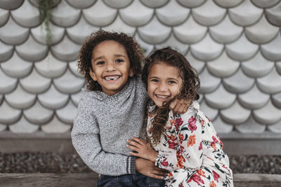 Cute siblings smiling and laughing while hugging