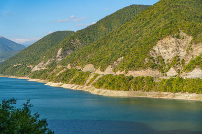 Scenic view of sea by mountains against sky