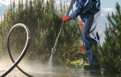 Low section of man washing street standing by plants