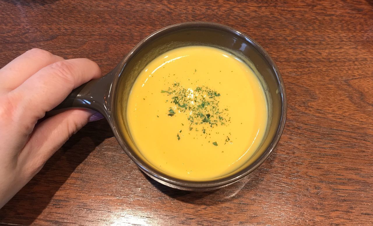 HIGH ANGLE VIEW OF HAND HOLDING BOWL OF SOUP