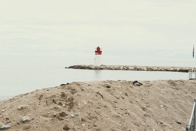 Lighthouse by sea against sky