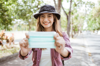 Portrait of smiling young woman holding smart phone