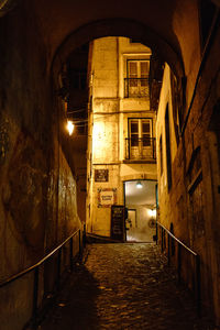 Empty alley amidst buildings in city at night