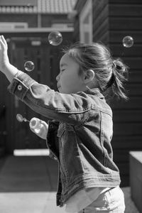 Side view of girl playing with bubbles