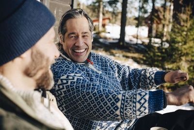 Cheerful mature man gesturing while talking with friend