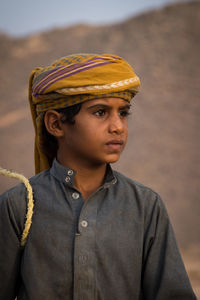 Thoughtful boy wearing traditional clothing while standing at desert