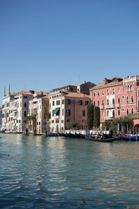 Canal amidst buildings against clear blue sky