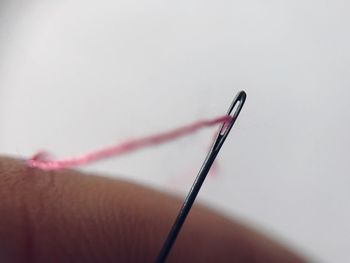Close-up of human hand holding needle and thread