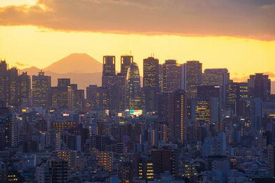 Illuminated cityscape against sky during sunset