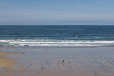 Scenic view of sea against sky with people walking