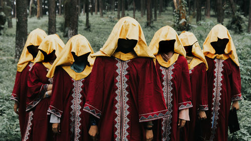 Spooky women standing against trees in forest