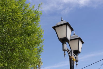 Low angle view of street lights by tree against sky