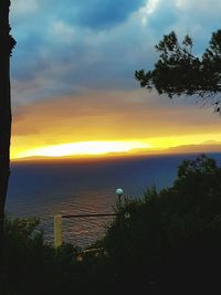 Scenic view of sea against cloudy sky at sunset