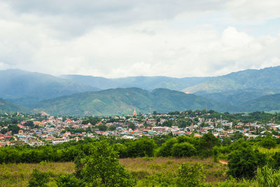 Scenic view of townscape by mountains against sky