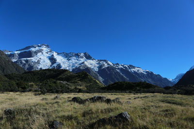 Scenic view of mt cook by field against clear blue sky