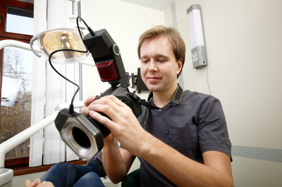 Happy young man photographing friend in room