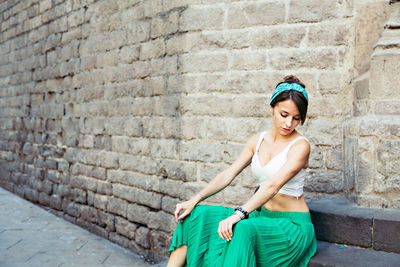 Portrait of young woman standing against brick wall