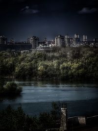 Scenic view of river by buildings against sky